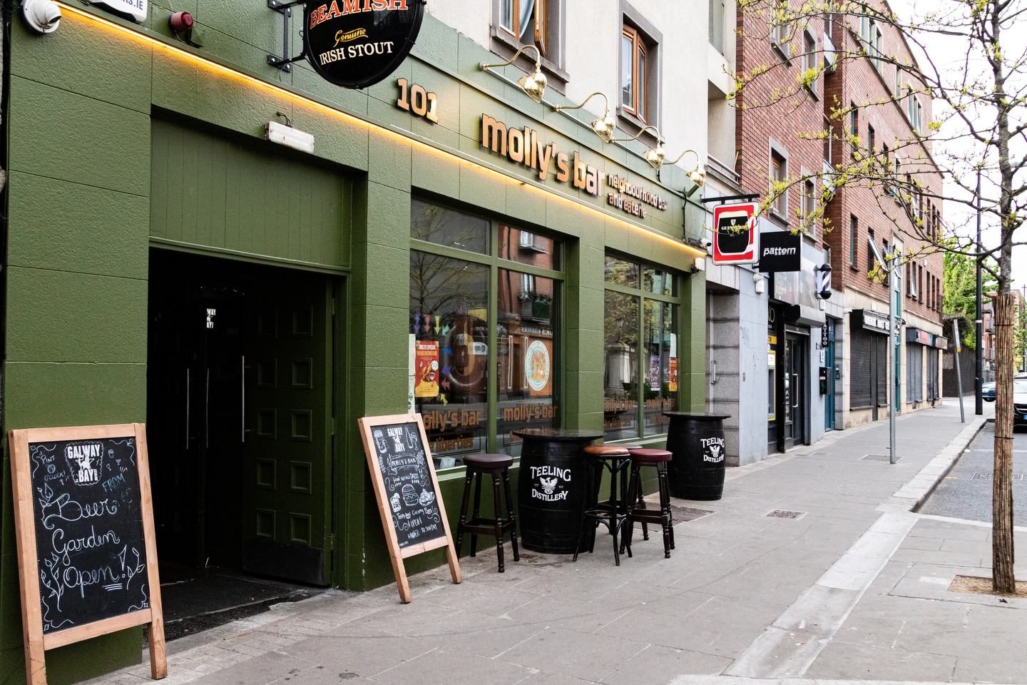 The green front of Molly's Bar at 101 Francis Street: gold lettering, brass lamps, chalkboards and barrel tables on the footpath.